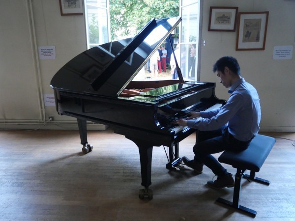 Un élève jouant du piano dans la salle de réunions de l'AX